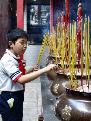 Jeune garon dposant un baton d'encens